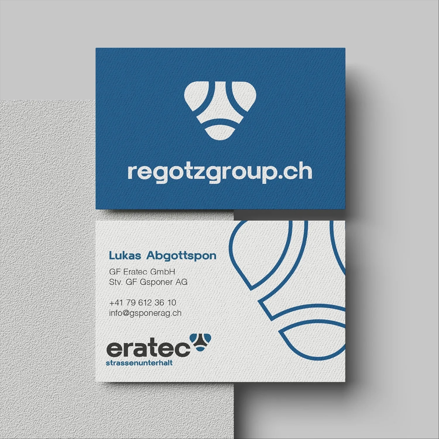 Visitenkarte: blaue Vorderseite mit Bildmarke und regotzgroup.ch, weisse Rückseite mit Kontaktangaben und Eratec-Logo.